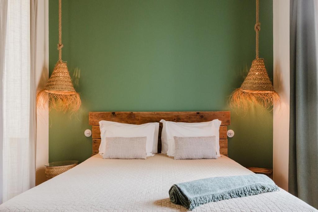 Interior de um quarto da Villa Galega com parede verde e iluminação artesanal